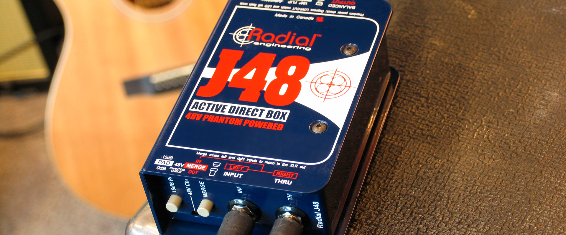 Radial J48 active direct box, dramatic close hero shot beside an acoustic guitar